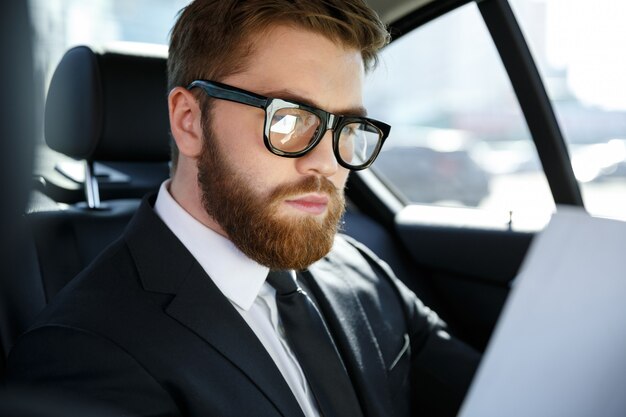 Concentrated young businessman analyzing documents while traveling