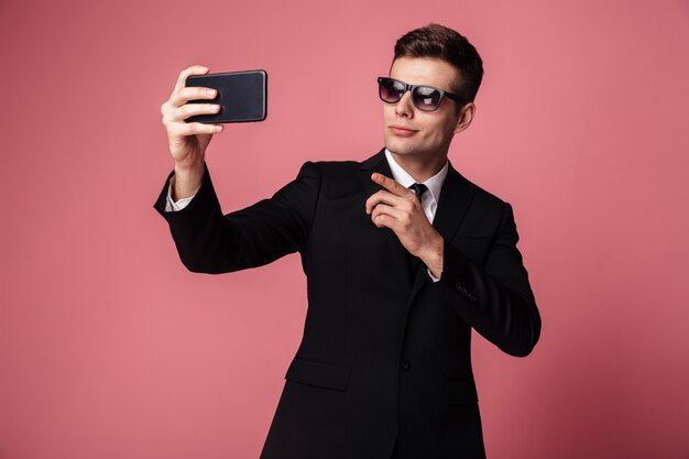 Concentrated young businessman make selfie by mobile phone.