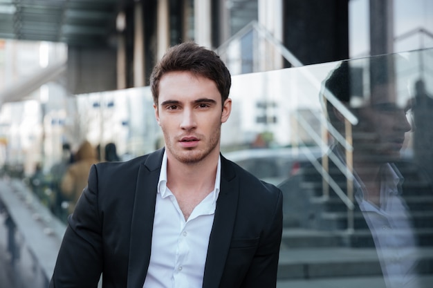 Concentrated young businessman walking near business center