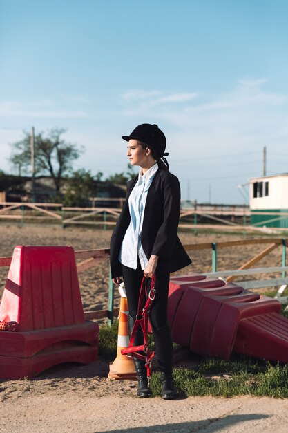 Concentrated young cowgirl standing outdoors