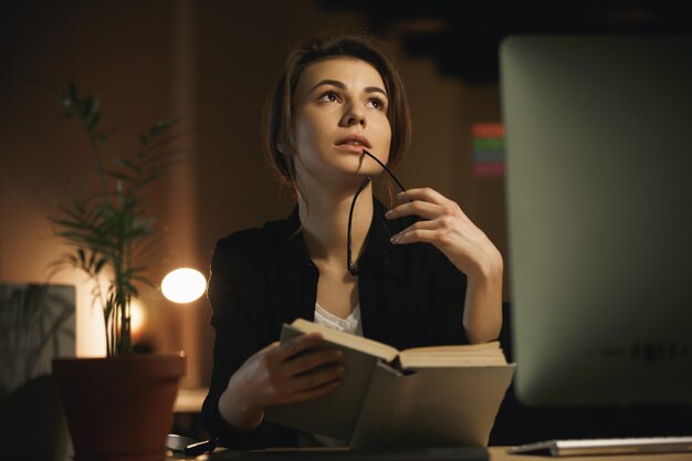 Concentrated young lady designer reading book.