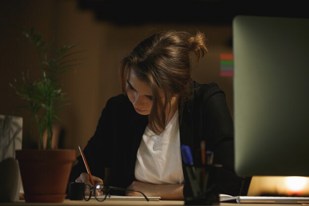 Concentrated young lady designer sitting in office