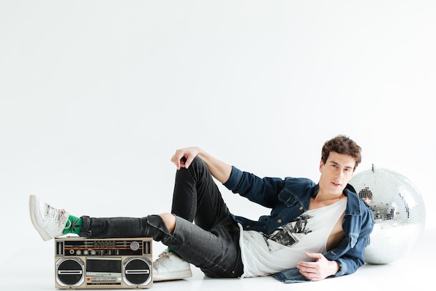 Free photo concentrated young man with disco ball and boombox.