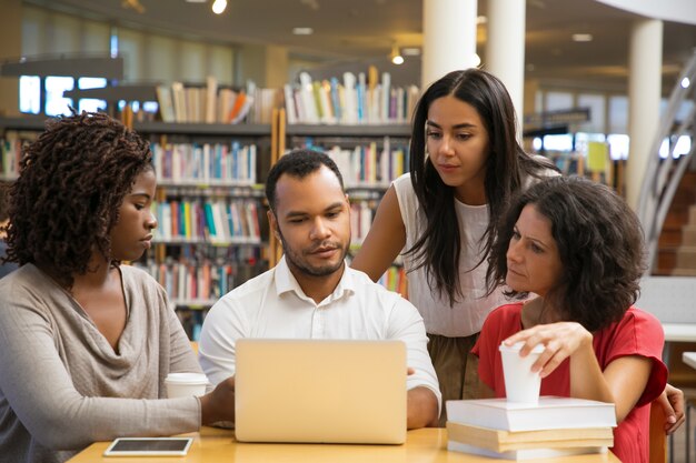 Concentrated young people reading information from laptop