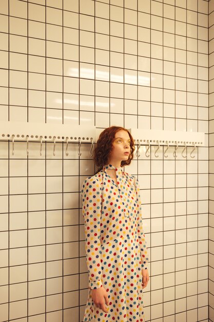 Concentrated young redhead curly lady standing in cafe