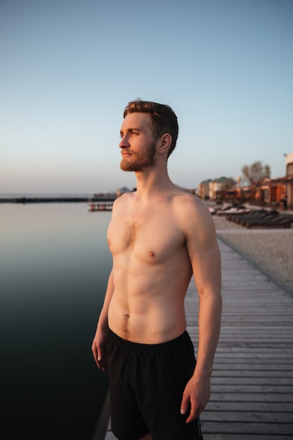 Foto gratuita giovane sportivo concentrato che sta alla spiaggia