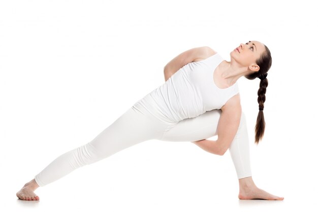 Concentrated young woman doing yoga exercises