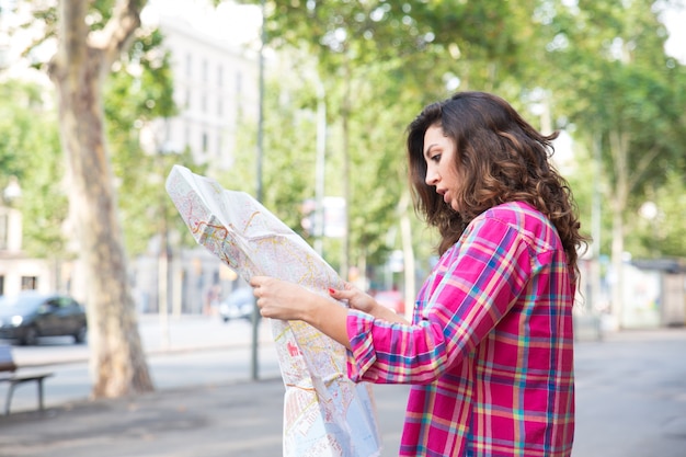 地図上で光景を見つけている集中した若い女性