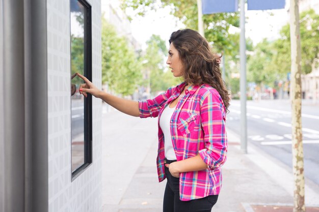 Concentrated young woman touching digital screen