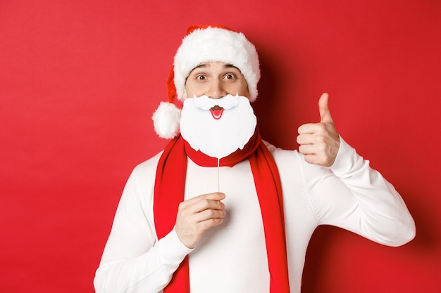 Concept of christmas winter holidays and celebration portrait of funny man in santa hat holding bear...