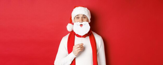 Concept of christmas winter holidays and celebration portrait of funny man in santa hat holding bear...