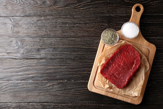 Concept of cooking with raw beef steak on wooden background