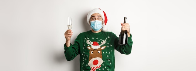 Free photo concept of covid and christmas holidays happy man in face mask and santa hat celebrating new year wi