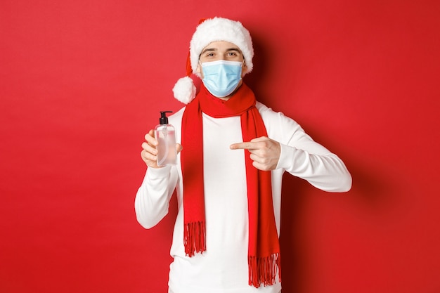 Concept of covid christmas and holidays during pandemic handsome happy man in santa hat and medical ...