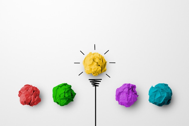 Концепция творческой идеи и новаторства. бумажный шарик желтого цвета, выдающаяся разная группа с символом лампочки