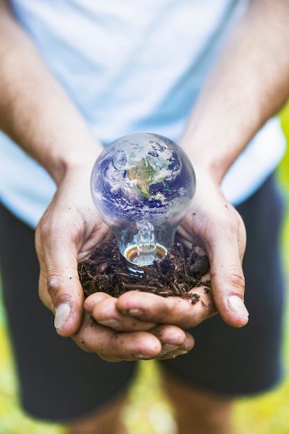 Concept hands holding Earth in bulb