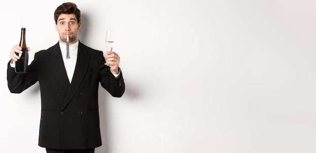 Concept of holidays party and celebration portrait of handsome guy in black suit raising bottle of c