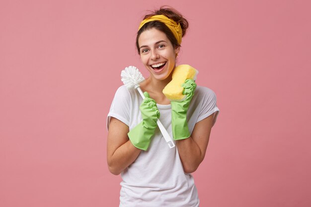 Concept of hygiene, cleaning, cleanliness, housework and housekeeping. portrait of casually dressed young Caucasian housewife holding toilet brush and sponge while doing household chores
