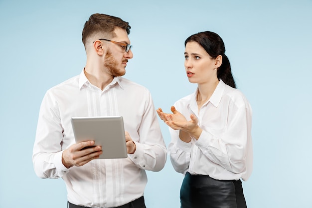 Concept of partnership in business. Young emotional man and woman against blue background at studio. Human emotions and partnership concept