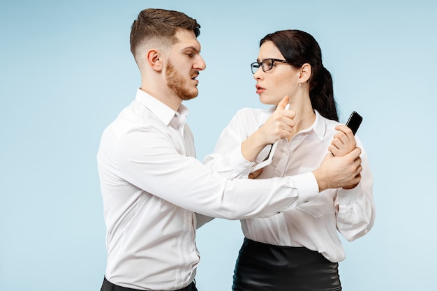 Concept of partnership in business. Young emotional man and woman against blue background at studio. Human emotions and partnership concept