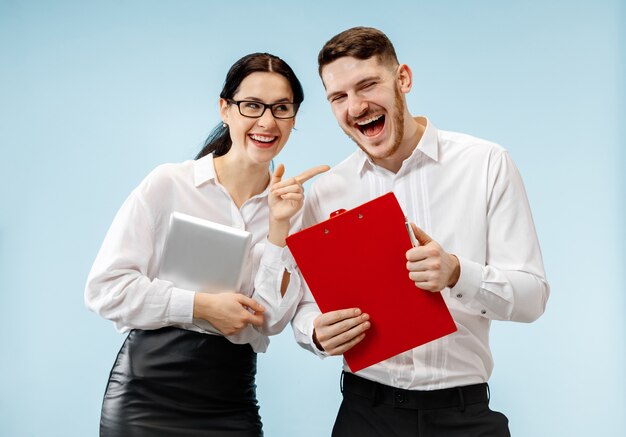 Concept of partnership in business. Young happy smiling man and woman standing against blue background at studio