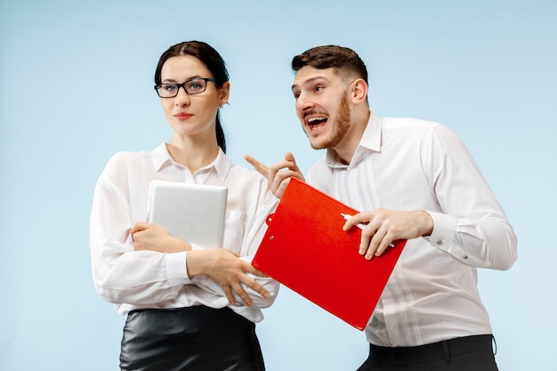 Concept of partnership in business. Young happy smiling man and woman standing against blue background at studio