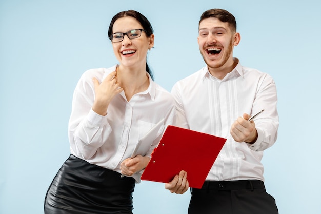 Concept of partnership in business. Young happy smiling man and woman standing against blue background at studio