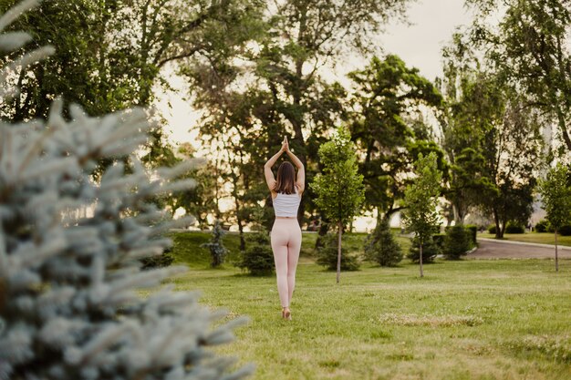 Concept of peace and mental health, young woman in pink leggings stands in palm tree pose in yoga.