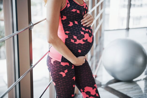 Концепция беременной женщины занимается спортом и фитнесом и ведет здоровый образ жизни в спортзале