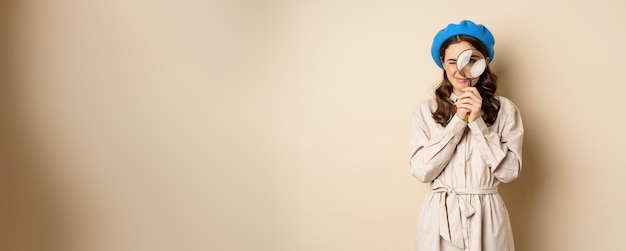 Free photo concept of search young stylish girl in detective clothing looking through magnifying glass big eye