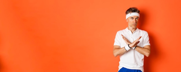 Free photo concept of sport fitness and lifestyle portrait of seriouslooking male coach showing cross sign tell