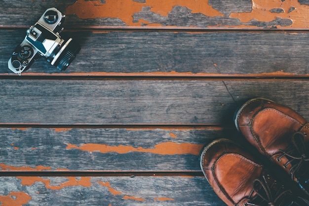 Concept of travel and explorer - old vinatge camera and leather boot on wooden background