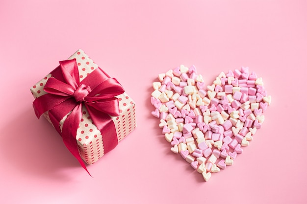 The concept of Valentine's day. Gift box with red bow on pink.
