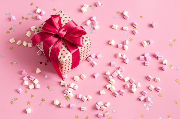 The concept of Valentine's day. Gift box with red bow on pink.