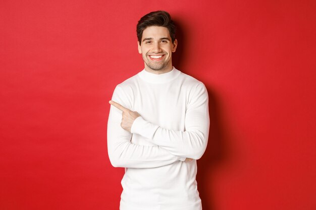 Concept of winter holidays christmas and lifestyle portrait of attractive man in white sweater point...