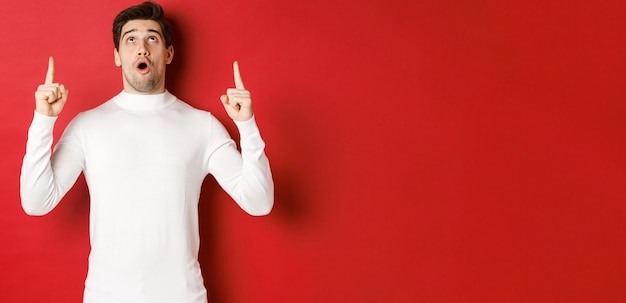 Concept of winter holidays portrait of handsome surprised man in white sweater reacting to new year