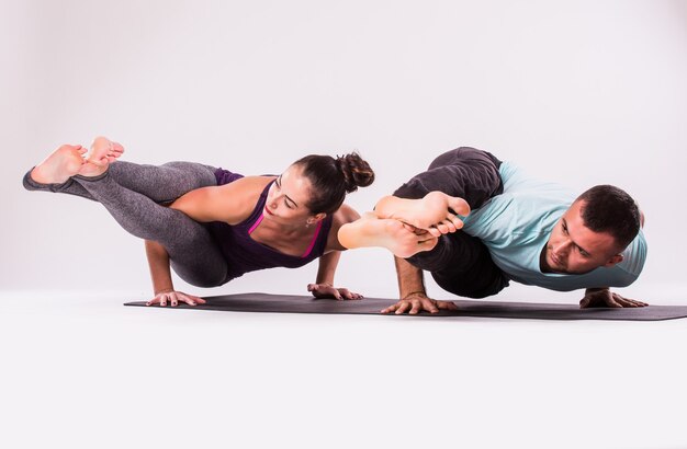 Концепция упражнений йоги. Молодая здоровая пара в позе йоги на белом фоне