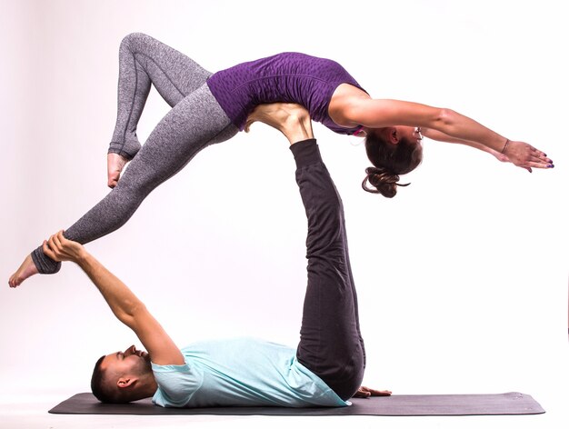 Concept of Yoga exercises. Young healthy couple in yoga position on white background