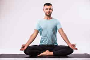Foto gratuita concetto di yoga. uomo bello che fa esercizio di yoga isolato su sfondo bianco