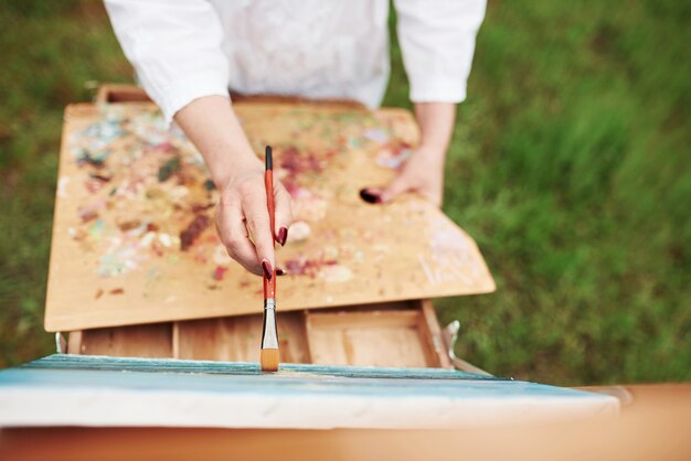 Concezione della pittura. foto della mano della donna con la spazzola rossa