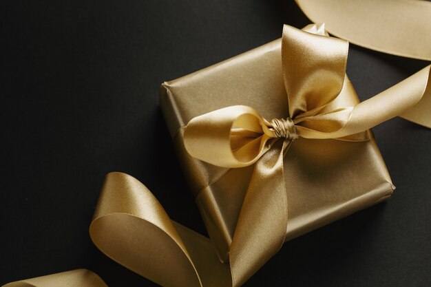暗い上のリボンと金色の贈り物と概念的な背景。上面図