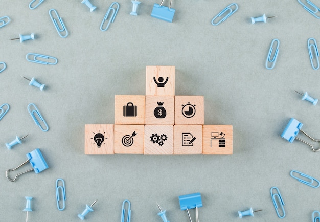 Conceptual of business office with wooden blocks with icons, paperclips, binder clips top view.