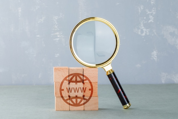 Conceptual of internet search with wooden blocks with internet icon, magnifying glass side view.