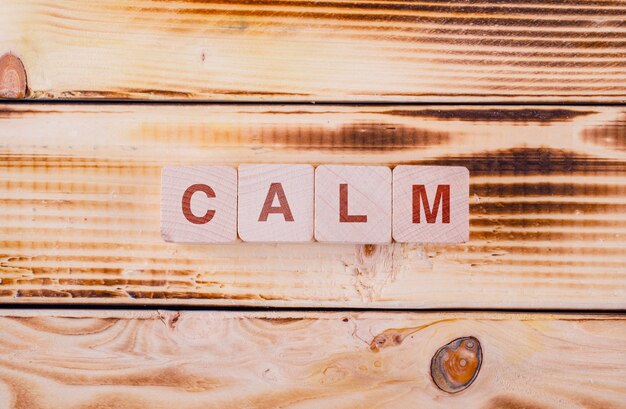 Conceptual of motivation with wooden blocks with typed on it calm on wooden table flat lay.