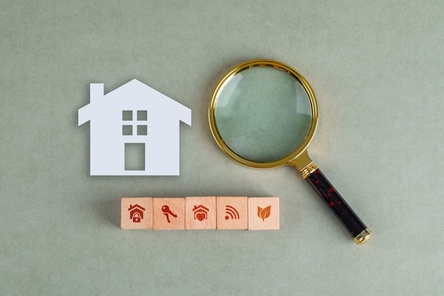 Концептуальный поиск недвижимости с деревянными блоками, бумажным домашним значком и увеличительным стеклом.