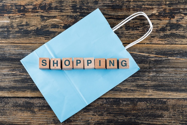 Conceptual of shopping with wooden blocks, shopping bag on wooden table flat lay.