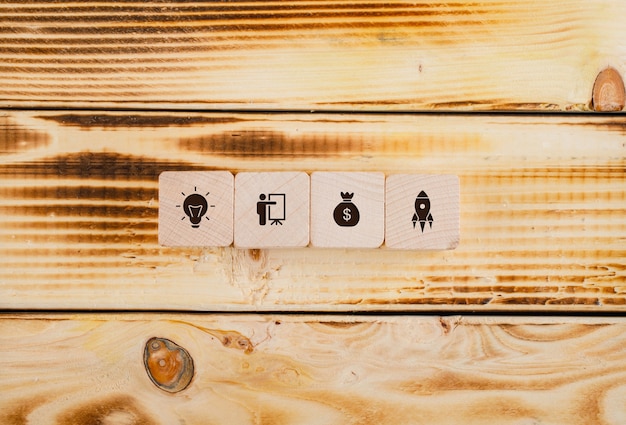 Conceptual of start up and business. with wooden blocks with icons on it on wooden table flat lay.