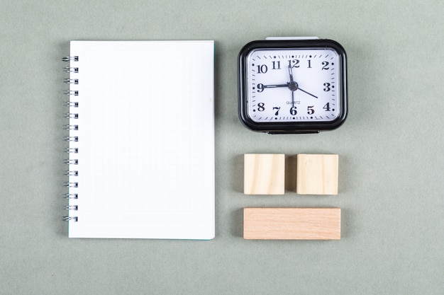 Conceptual of time management and brainstorming. with clock, notebook, wooden blocks on gray background top view. horizontal image