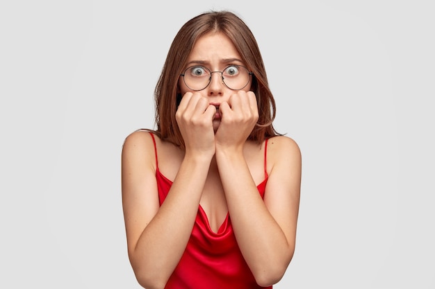 Free photo concerned brunette young woman posing against the white wall