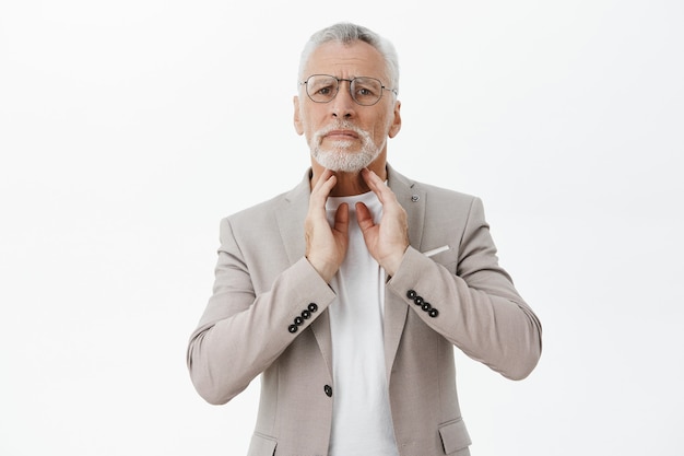 Concerned elderly man touching his neck, complaining sore throat